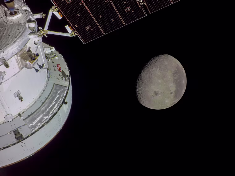 Image: The Orion spacecraft is seen in the foreground lit up by the Sun. A waxing gibbous Moon is visible in the background. Orientale basin, a 600-mile-wide impact crater ringed by mountains, is visible toward the center bottom of the Moon. This basin straddles the Moon’s near and far sides. To the left of Orientale, which has a patch of ancient lava in its basin, is the far side; this is the hemisphere we don’t get to see from Earth. To the right of Orientale is the near side, the hemisphere we see every day from Earth. The nearside is notable for giant, dark patches of ancient lave flows that cover its surface.