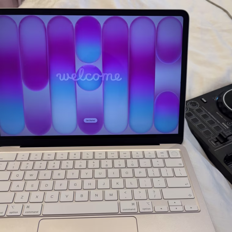 The Macbook Neo hooked up to the Pioneer DDJ on a pink bedspread.