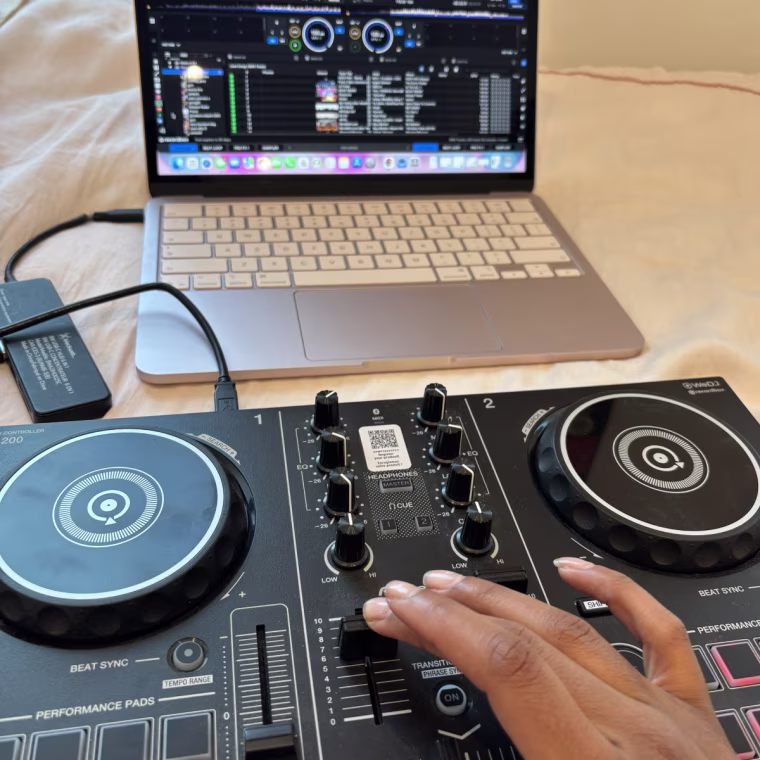 The Pioneer DDJ controller laying on a pink bedspread with the lights on.