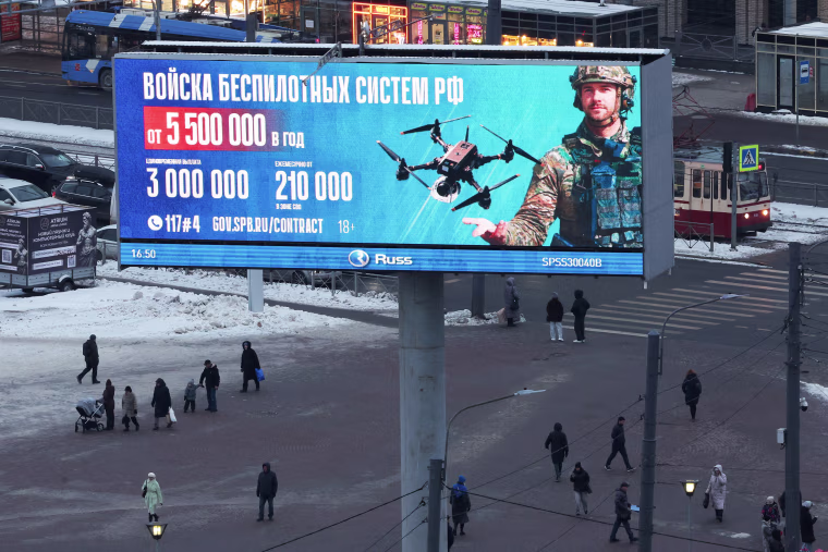 FILE PHOTO: People walk under an ad promoting contract military service in Russian army, in St Petersburg