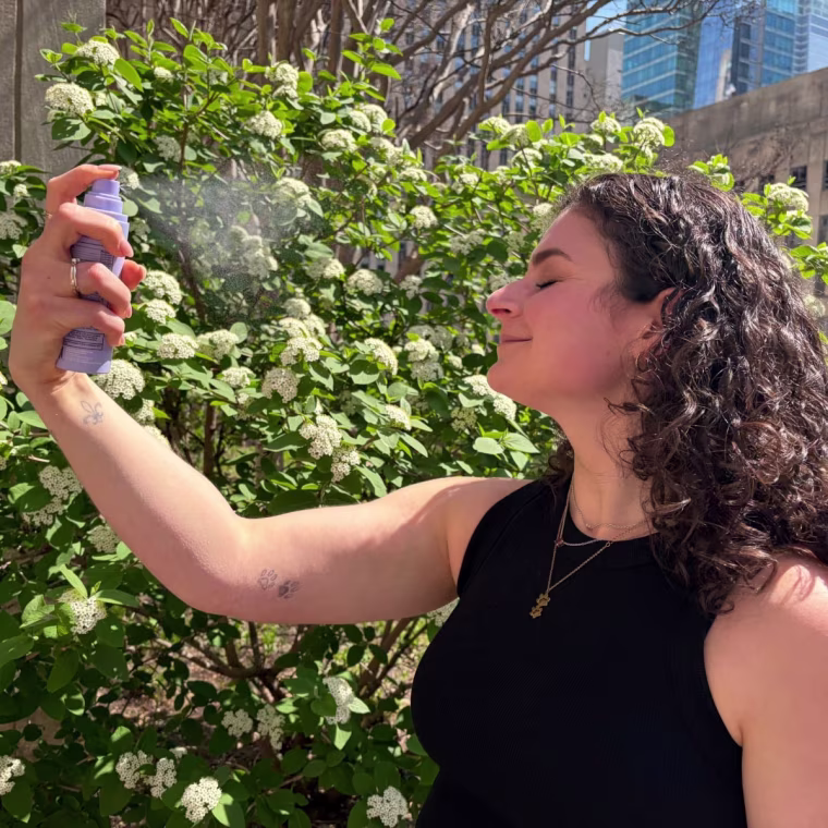 Woman spraying sunscreen mist on face
