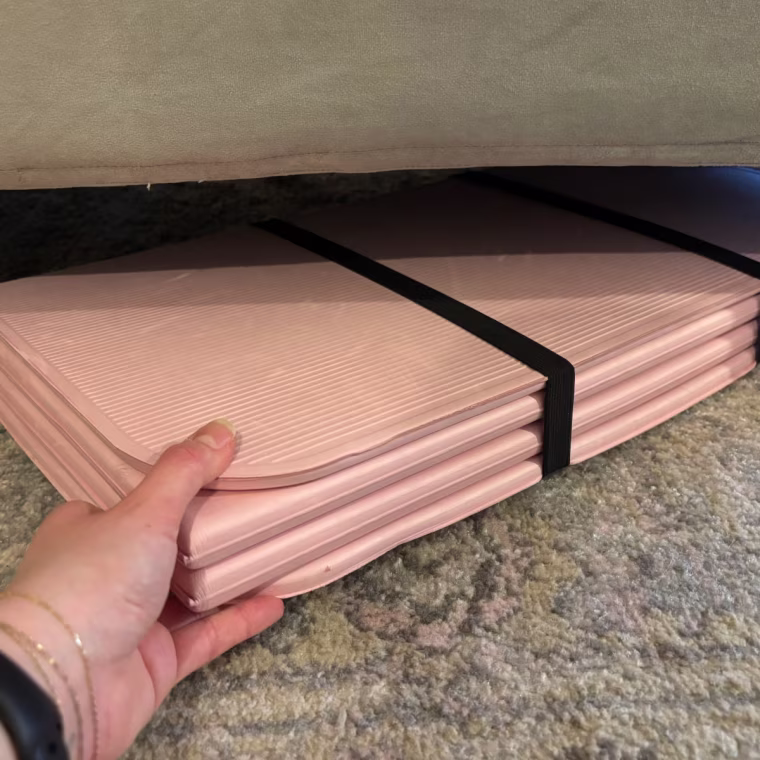 Woman sliding Stakt mat underneath a couch