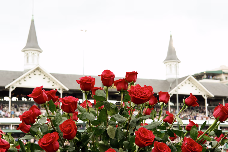 Red roses appear in the foreground before the twin spires of Churchill Downs.