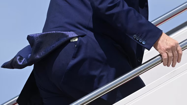 A 50 dollar bill poking up from a seat pocket in President Trump's pants as he ascends the stairs to Air Force One.