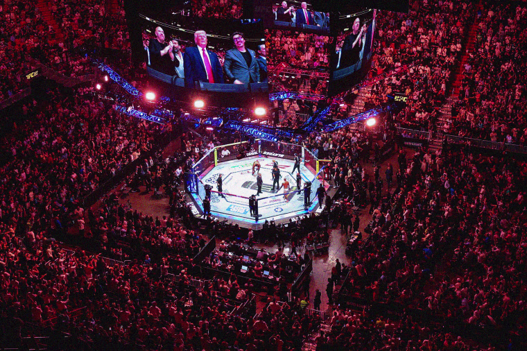 Aerial view of a stadium with a UFC ring and TV screens showing President Donald Trump, Dana White and Hunter Campbel.. 