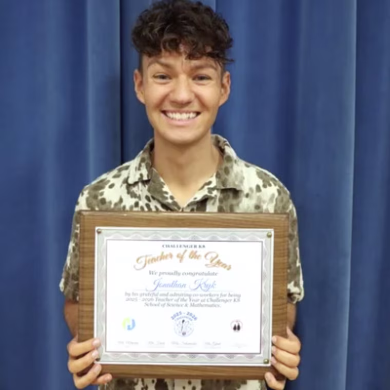 A young man holding an award certificate and smiling broadly.