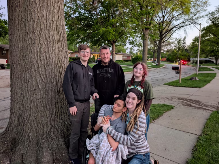 Anna Keyzer and family members pose by a tree on a sidewalk for a family portrait