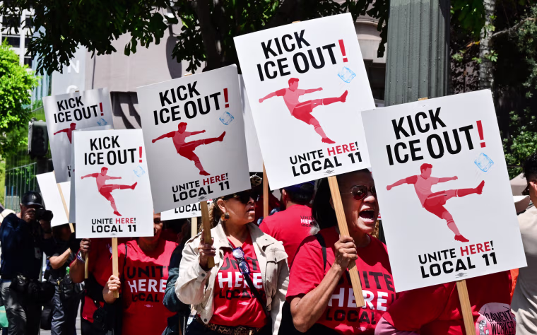 Protestors stand in a line holding signs that read "Kick ICE Out! Unite Here! Local 11"