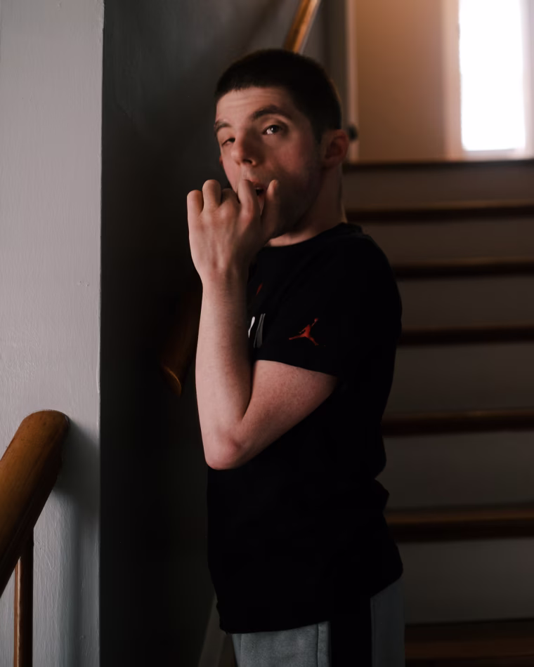 Jason stands on a set of stairs inside of his home