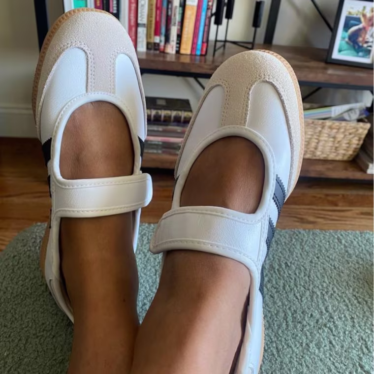 A person wearing Adidas Mary Janes with feet crossed