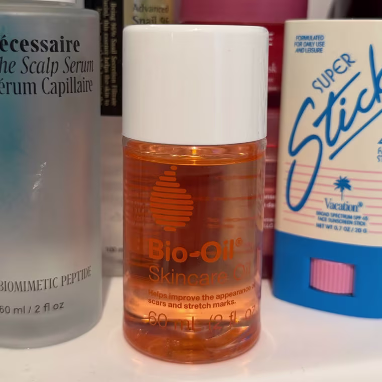 Bio-oil on a sink next to other beauty products.
