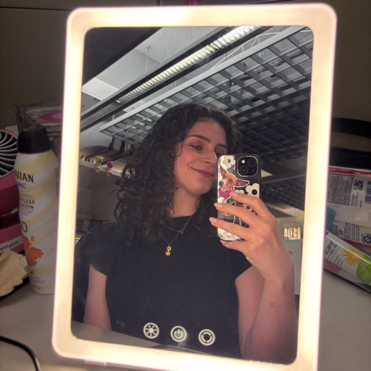 A woman taking a picture of herself in the Ilios Lighting Slim Mirror.