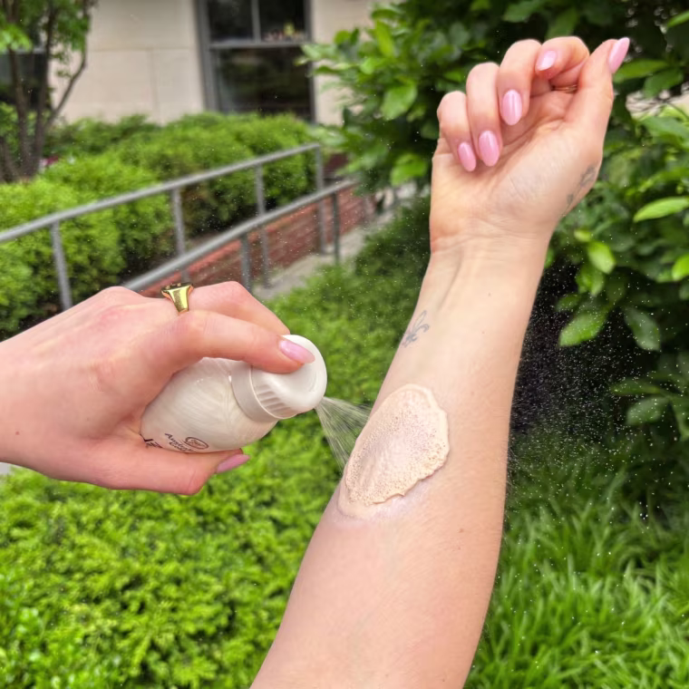 A woman applying Australian Gold’s SPF Tinted Mineral Sunscreen Spray.