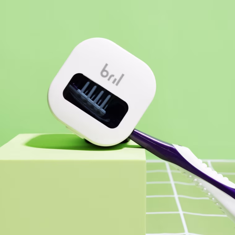 Bril toothbrush holder and cleaner on a green background.