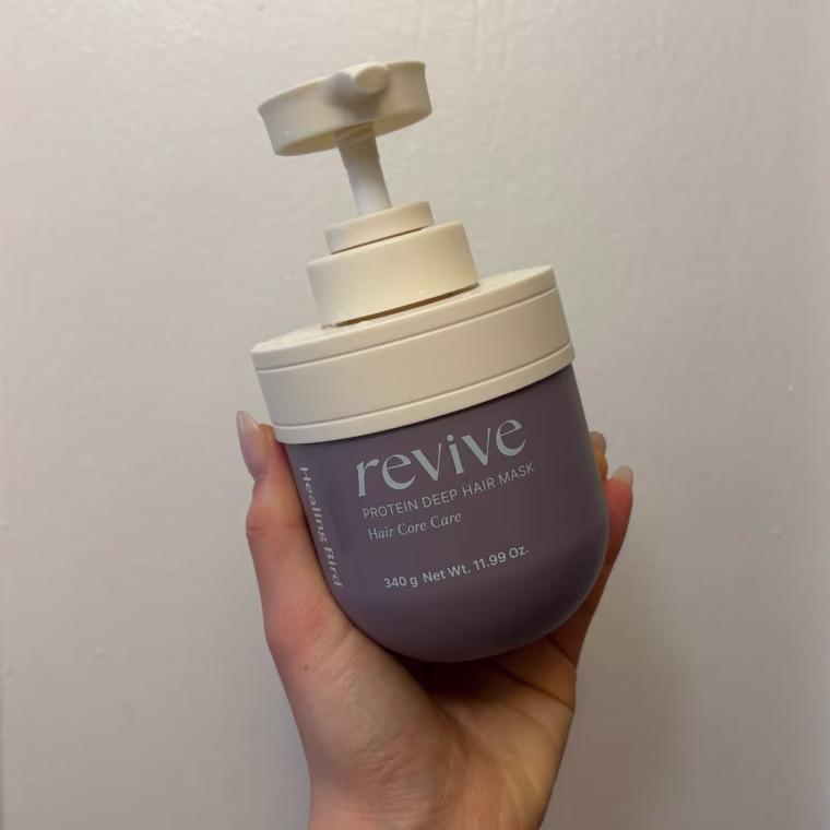 Hand holding the Revive Protein mask against a white door.
