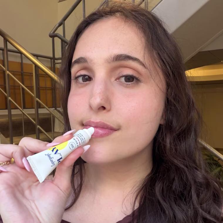Woman applying Supergoop lip balm