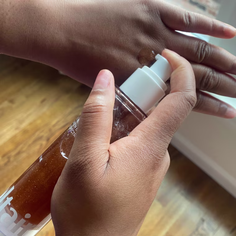 Woman applying sunscreen oil to her hand