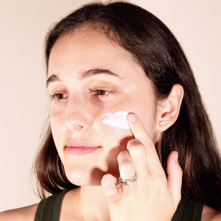 Woman applying sunscreen on face