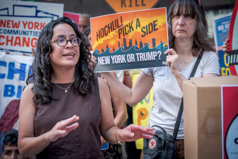 Claire Valdez speaks outside in front of people holding signs