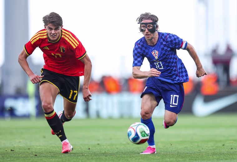 Charles De Ketelaere, left, and Luka Modric run on the soccer field