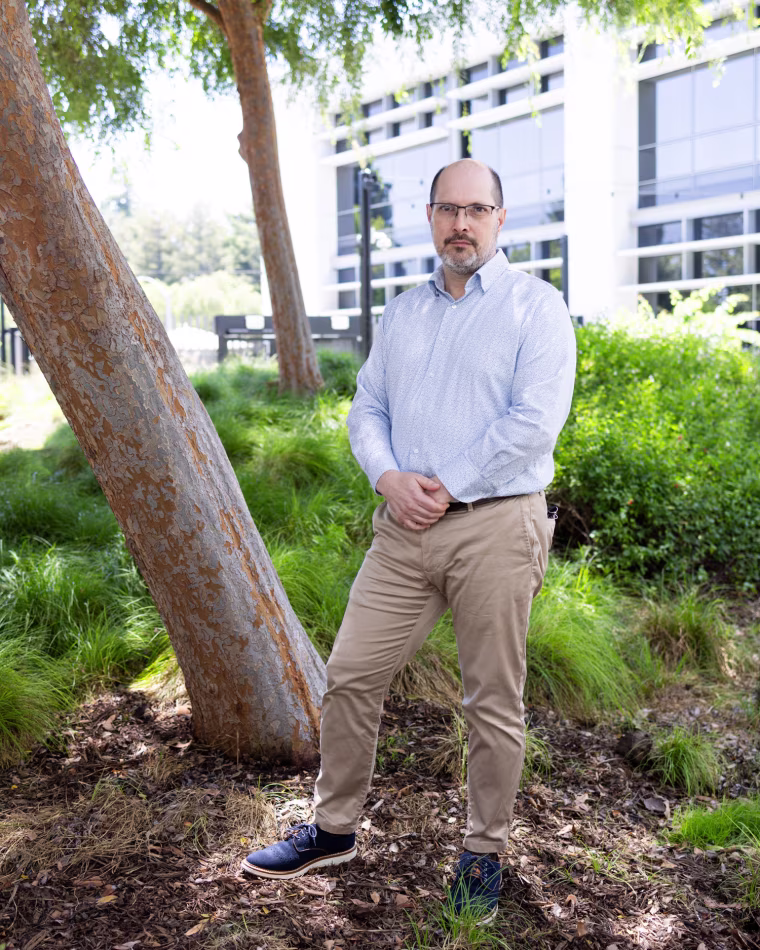 Joseph South stands in a tree patch outside of a building