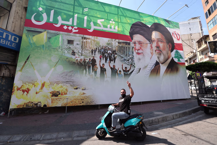 A man flashes the victory sign in front of a billboard depicting the late Iranian leader Ayatollah Ali Khamenei and Iranian Supreme Leader Ayatollah Mojtaba Khamenei in Beirut, Lebanon, on June 15, 2026.