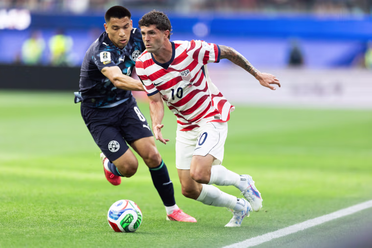 Christian Pulisic runs with the soccer ball while defended by Diego Gomez