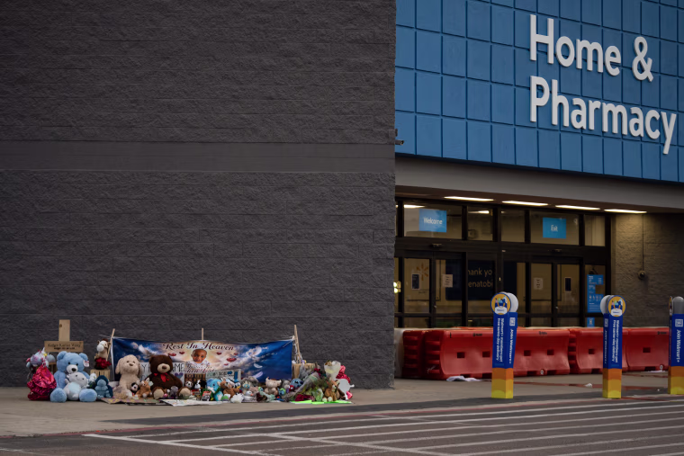A makeshift memorial with balloons and stuffed animals in front of a Wal-Mart.
