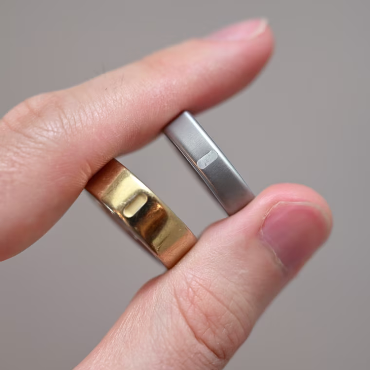 A close up of the Oura Ring 5 and Oura Ring 4 in a person’s hand.