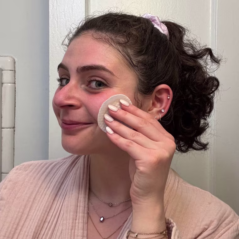 Woman applying toner pad to face