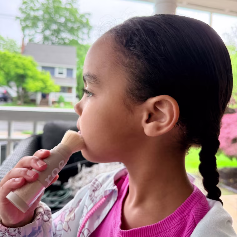 Child applying sunscreen powder on face