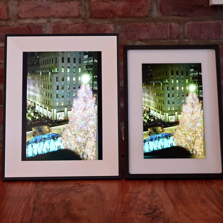 A side-by-side of the Aura Aspen and Skylight Frame 2, both displaying the same photo of a Christmas tree lit up in Rockefeller Center.