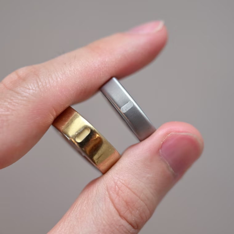 A close up of the Oura Ring 5 and Oura Ring 4 in a person’s hand.