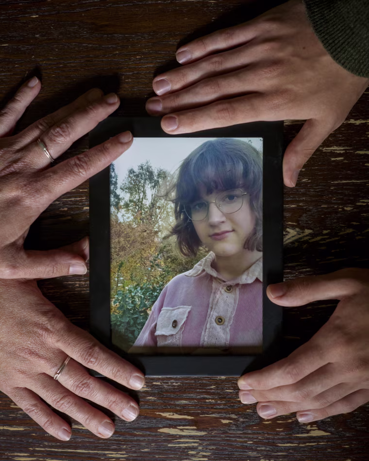 May Pollard's mother and brothers hands cradle a photo of May.