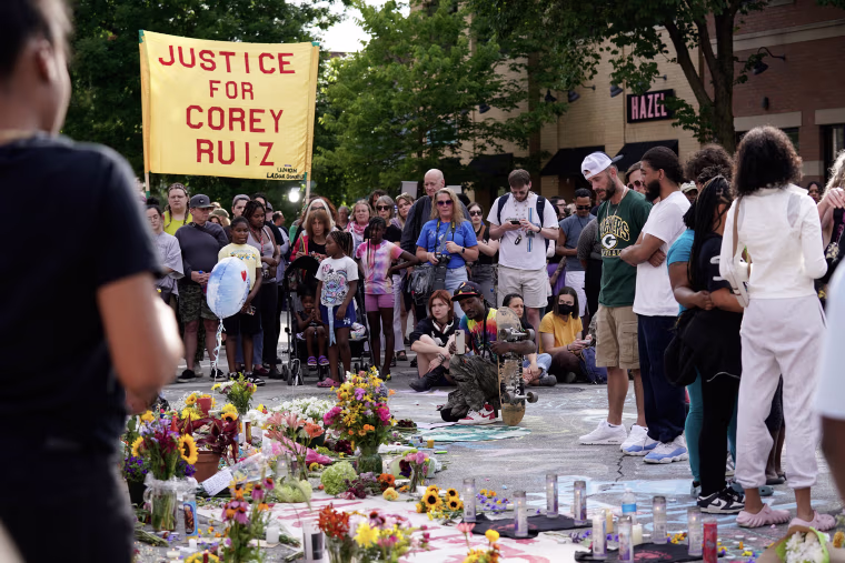 A makeshift memorial in an intersection with people crowded around it.