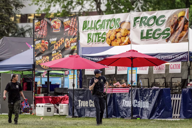 A law enforcement officer walking in front of a food vendors booth.