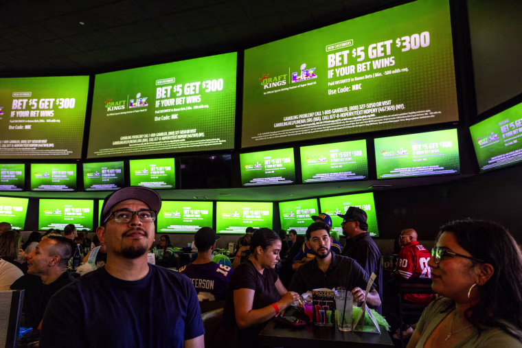 A commercial for Draft Kings during the Super Bowl LX broadcast on television screens at a bar