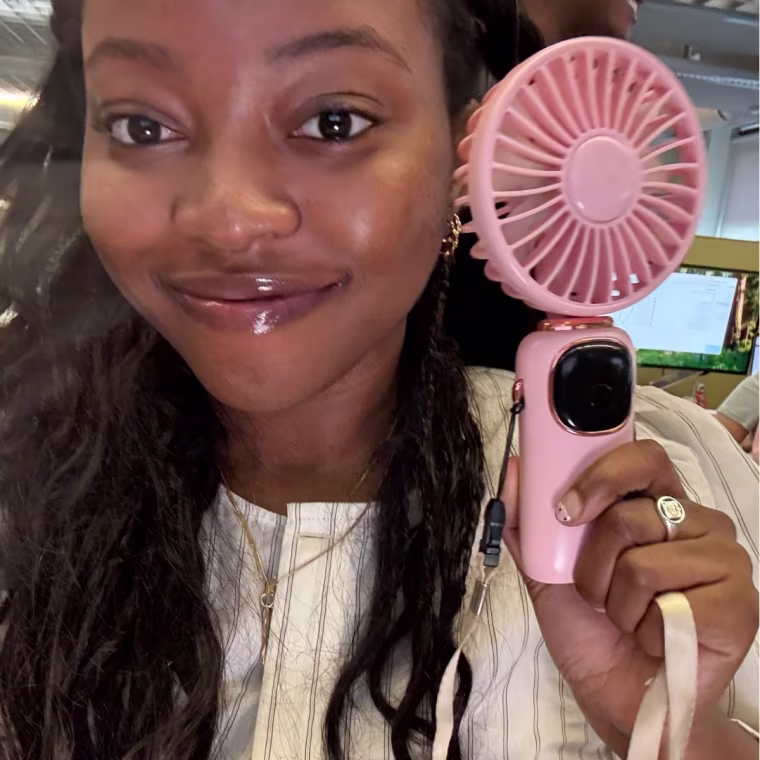 Woman holding pink handheld fan.
