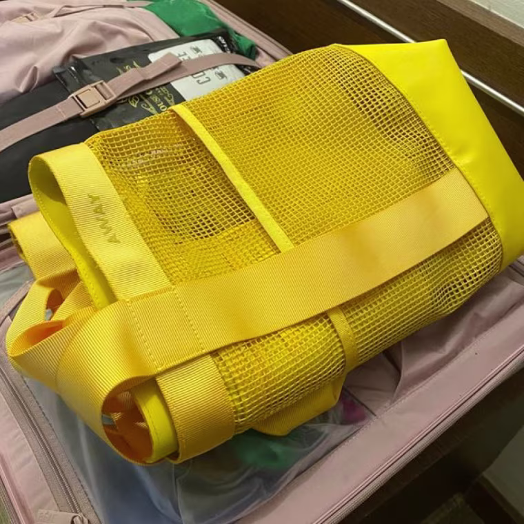Yellow Away bag sitting inside a packed suitcase