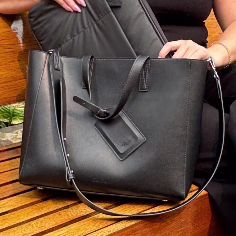 Woman sitting with the Haven Laptop Tote on her right side.