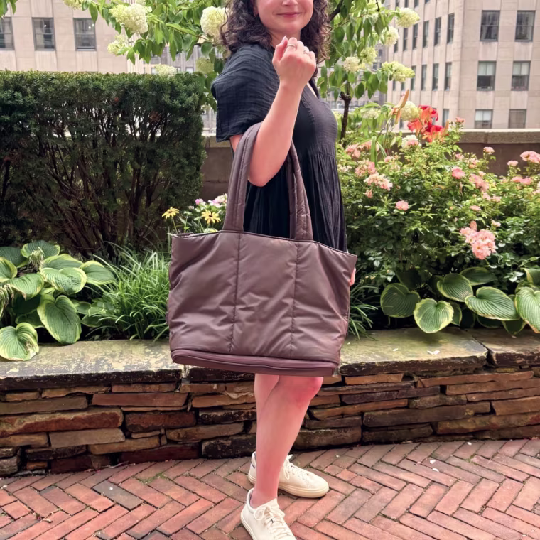 Woman holding the Luka Expandable Tote on right arm.