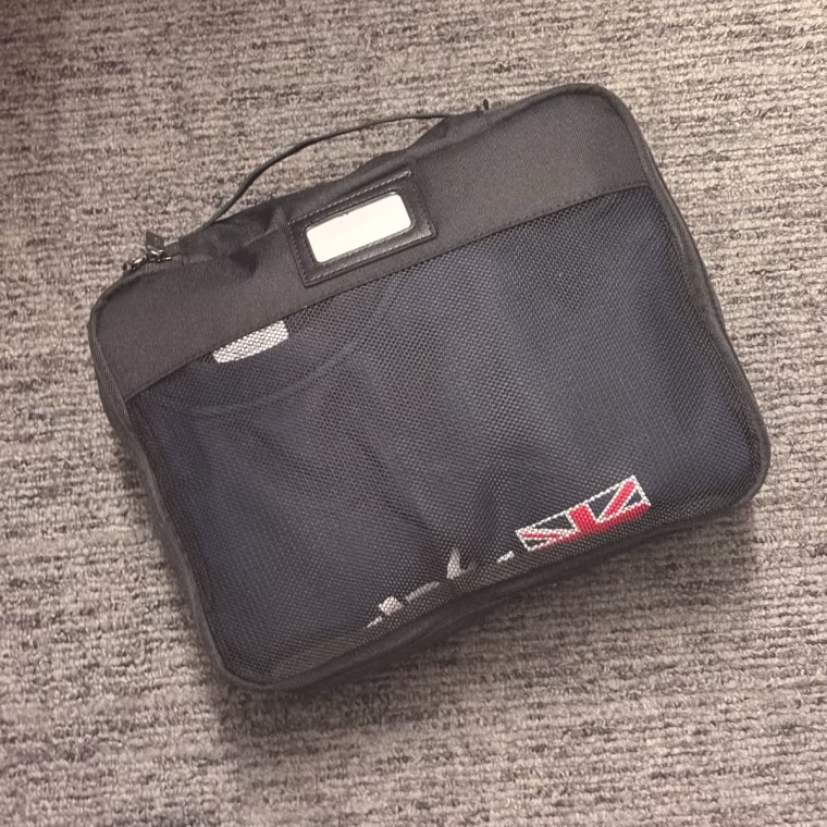 Small Calpak packing cube packed with a sweater on carpet.