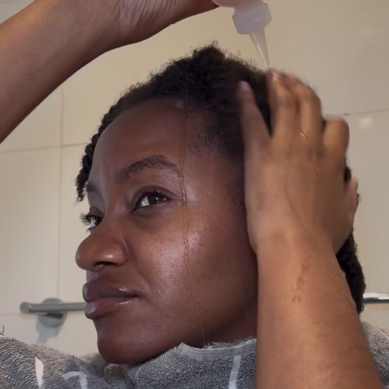 Woman applying hair rinse to natural hair