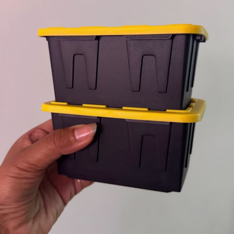 Person holding miniature storage bins stacked on top of each other.