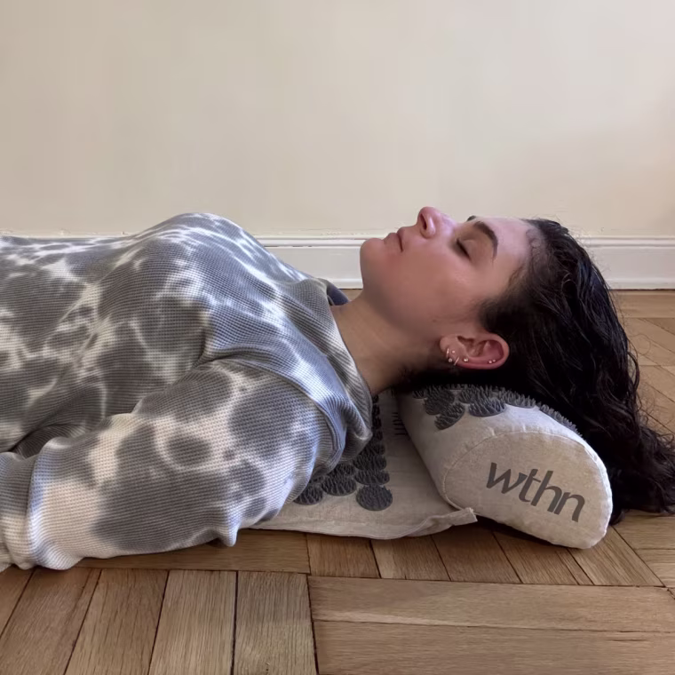 A woman laying on Wthn’s Acupressure Mat Set.