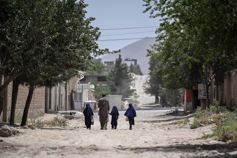 Afghan schoolgirls along with their father walking in the middle of the street.