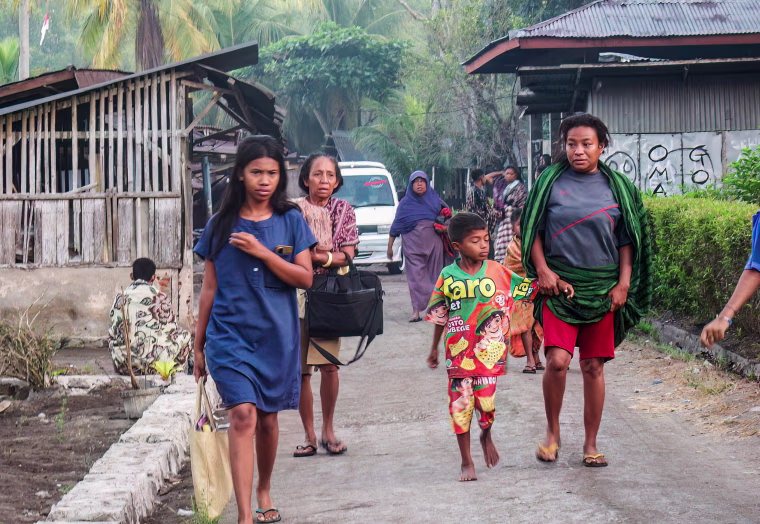 Villagers walk in the middle of the street.