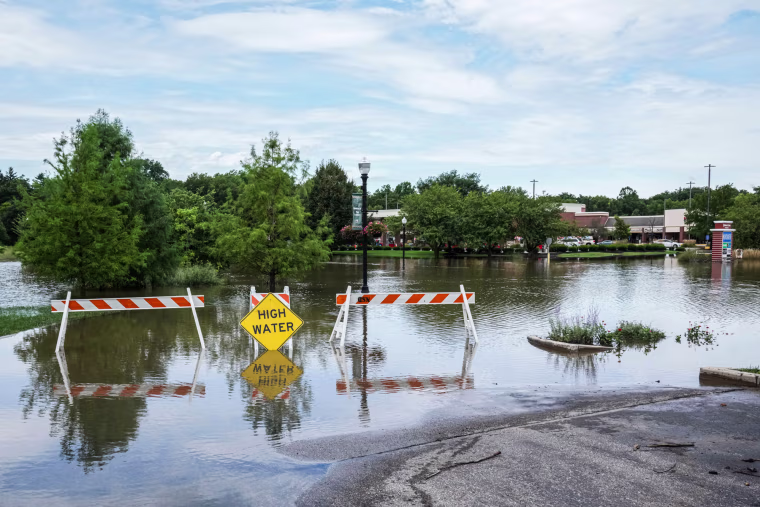 Floodwater sits on a road behind a "high water" caution sign