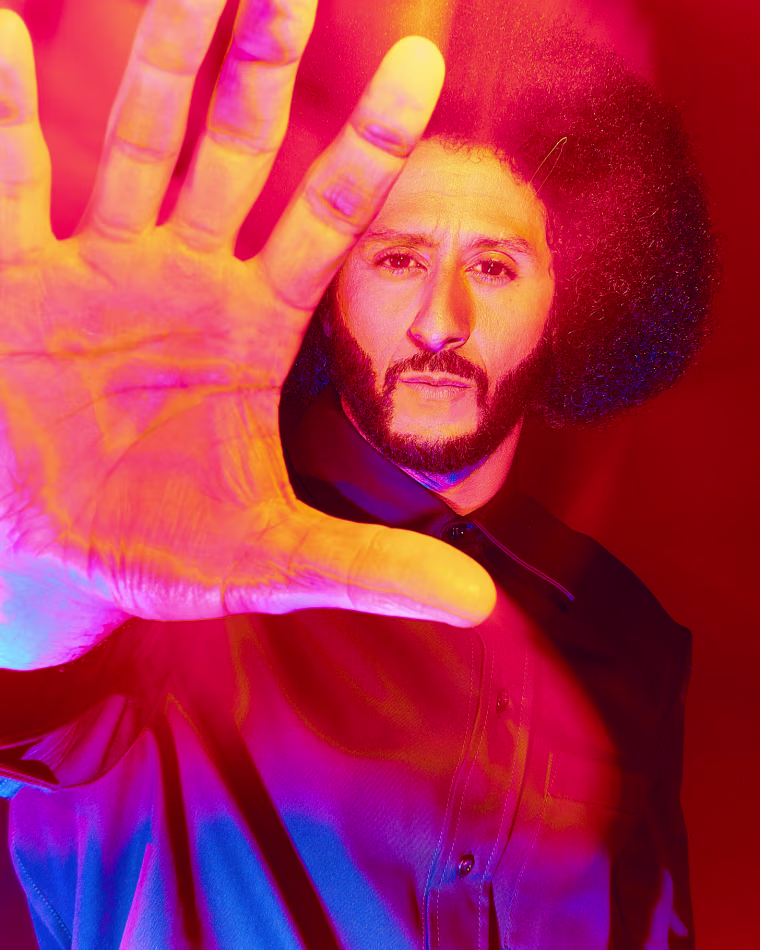 Colin Kaepernick holds his hand toward the camera