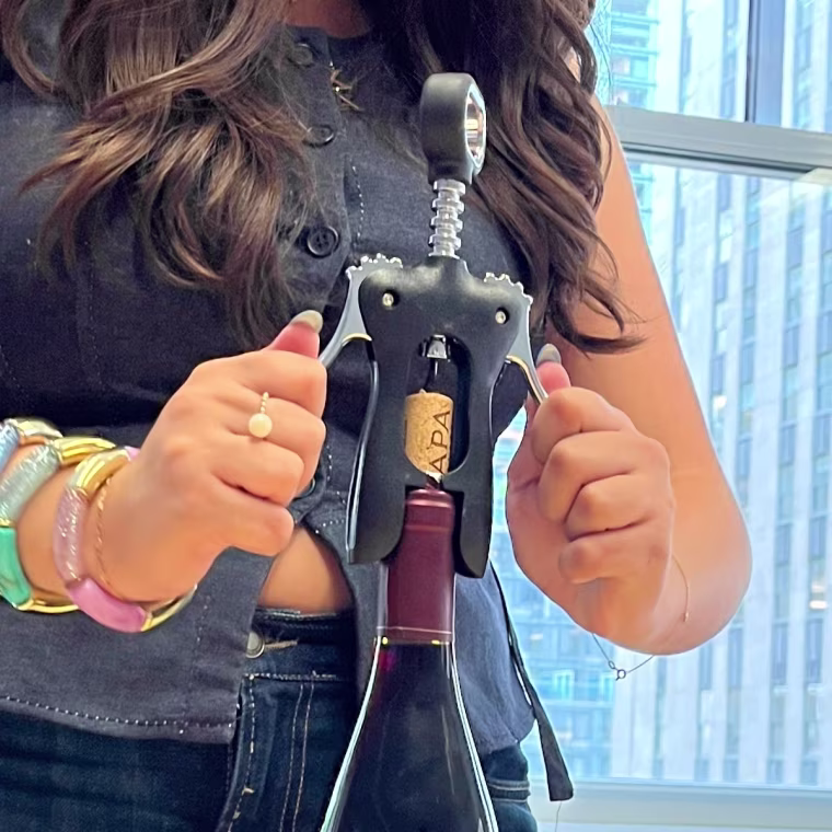 Pushing down the arms of the Houdini wine opener to free the cork from the bottle.
